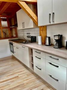 a kitchen with white cabinets and a wooden floor at Wanderurlaub mit und ohne Hund! in Harra
