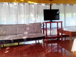 a living room with a couch and a flat screen tv at Casita Grau 2! Naturaleza y confort con Agua caliente,cocina y frigobar in Tarapoto