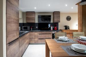 a kitchen with wooden cabinets and a table with chairs at APPALACHES Annecy Rent Lodge in Annecy