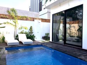 - une piscine en face d'un bâtiment avec deux chaises blanches dans l'établissement Villa Olive, à Dalung