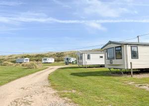 a campsite with two houses and a dirt road at Anchor Park in Happisburgh