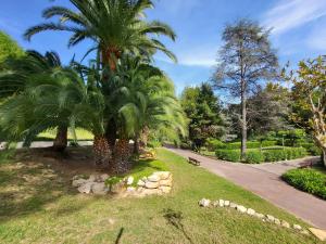 a park with two palm trees and a sidewalk at Évasion à deux, domaine prestigieux, jacuzzi et parking privés, piscine in Cannes