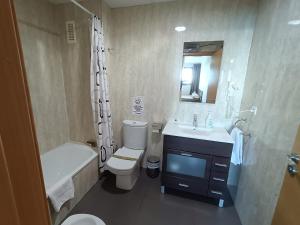 a bathroom with a sink and a toilet and a bath tub at Aparthotel El Faro in Cullera