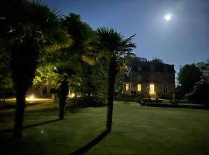 a man standing between two palm trees in front of a house at Manoir de la Marjolaine in Cabourg