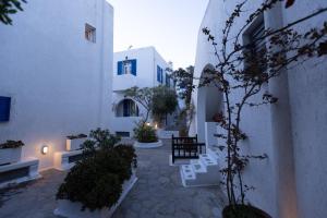 a courtyard with white buildings and plants and a bench at Petit Andromeda Mykonos I in Mikonos