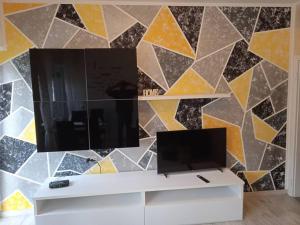 a living room with a tv and a mosaic wall at Casa Orchidea in Oria