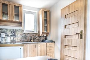 a kitchen with wooden cabinets and a door at Domki Letniskowe in Grzybowo +245 photos