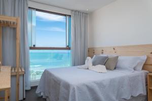 a bedroom with a white bed with a large window at Hotel Pousada Aloha in Maceió