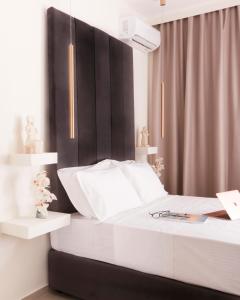 a bedroom with a white bed with a black headboard at Atlas Suites in Skiathos Town
