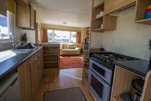 a kitchen with wooden cabinets and a stove top oven at 6 Berth Caravan For Hire With Decking At Manor Park In Norfolk Ref 23017s in Hunstanton