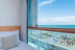 a bedroom with a bed and a view of the ocean at Hotel Pousada Aloha in Maceió