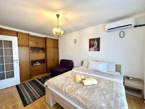 a bedroom with a bed and a purple chair at YellowHouse in Prishtinë