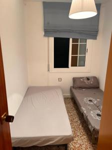 Habitación pequeña con 2 camas y ventana en Playa home, en Cunit