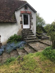 una pequeña casa con flores azules delante de ella en Ancien moulin du 18 ieme en Assé-le-Riboul