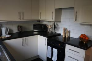 una cocina con armarios blancos y encimeras negras en Charming 2 Bed House - Family Friendly en Nottingham