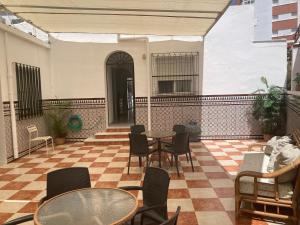 un patio con mesas y sillas en un suelo a cuadros en Hostal Avenida by Bossh! Hotels, en Chipiona