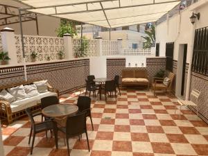 um pátio com mesas e cadeiras num piso xadrez em Hostal Avenida by Bossh! Hotels em Chipiona