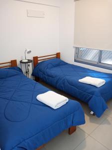 2 łóżka w pokoju z niebieską pościelą i białymi ręcznikami w obiekcie Vivanco w mieście Tigre