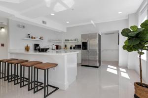 a kitchen with a bar with stools and a refrigerator at Roami at The Ralston in Miami