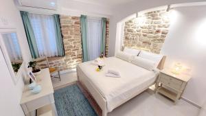 a bedroom with a white bed and a brick wall at Mouses Erato in Vathi