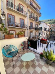 Un patio con sillas y una mesa en el balcón. en Torre's Camere & caffè en Monreale