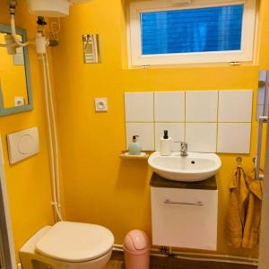 uma casa de banho amarela com um WC e um lavatório em Barbapappart - Un studio coloré dans le centre de Rouen em Rouen