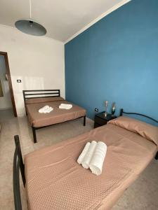 um quarto com 2 camas e uma parede azul em Casa Iole em Carbonia