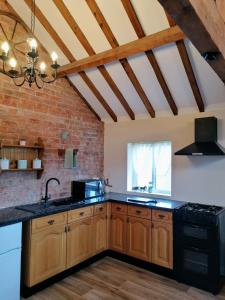 a kitchen with wooden cabinets and a brick wall at Poplar Cottage in Woodhall Spa