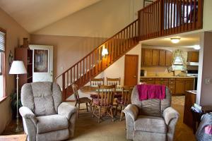 a living room with chairs and a table and a staircase at Pine Haven Beach House in Tawas City