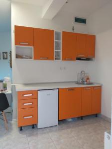kuchnia z pomarańczowymi szafkami i białą lodówką w obiekcie Apartmani Sladojević w mieście Mrkonjić Grad