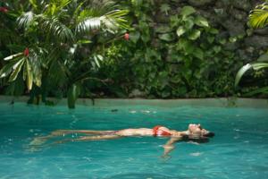 een vrouw drijvend in een zwembad in een tuin bij Madre Tierra Eco Habitat in Puerto Morelos