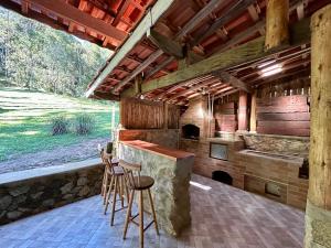 uma cozinha exterior com um balcão de pedra e bancos em Casa de Campo Vizinha da Lua em Monte Verde