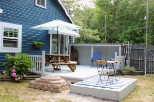 un patio con mesa y sombrilla en Cozy cottage just minutes from Lake Michigan! en Pentwater