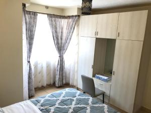 Schlafzimmer mit einem Bett, einem Schreibtisch und einem Fenster in der Unterkunft Maliaways Comfy Airbnb-Jkia in Nairobi