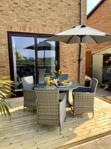 a table and chairs with an umbrella on a deck at Cinque Ports Snug - mins from Sea & Golf Course in Deal
