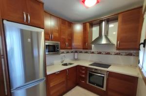 eine Küche mit Holzschränken und einem Kühlschrank aus Edelstahl in der Unterkunft LA CASA NUEVA 