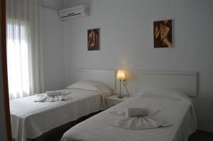 2 Betten in einem weißen Zimmer mit Fenster in der Unterkunft Nuevo Hotel Capitolio in Valdepeñas