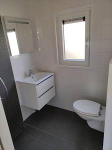 ein Bad mit einem WC, einem Waschbecken und einem Fenster in der Unterkunft Chalet Seepark Süsel in Süsel