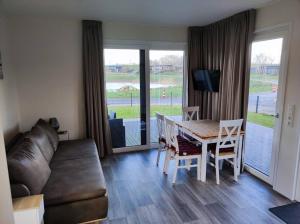 a living room with a couch and a table and chairs at Chalet Seepark Süsel in Süsel