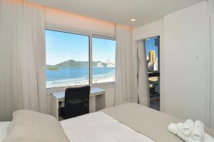 - une chambre avec un bureau et une vue sur la plage dans l'établissement Requinte com Vista Mar na Avenida Atlântica P2178, à Balneário Camboriú