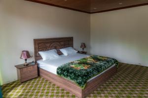 a bedroom with a bed and a night stand with two lamps at Greenwood Resort Skardu in Skardu