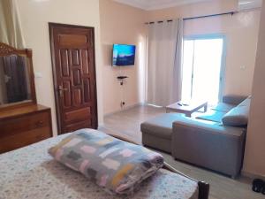 a bedroom with a bed and a couch and a tv at Appartement deux chambres salon à Saint-Louis in Saint-Louis