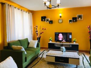 a living room with a green couch and a tv at Maliaways Comfy Airbnb-Jkia in Nairobi
