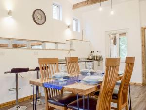 a kitchen with a table with chairs and a clock on the wall at Lletyr Saer in Pen-y-bont-fawr