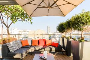 a patio with a couch and an umbrella at Luxe 3BR Penthouse w Jacuzzi&Parking&Mamad by HolyGuest in Tel Aviv