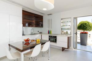 a kitchen with white cabinets and a table and chairs at Luxe 3BR Penthouse w Jacuzzi&Parking&Mamad by HolyGuest in Tel Aviv