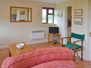 a living room with a couch and a table and a tv at Meadowview Cottage in Saint Osyth