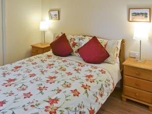 a bedroom with a bed with a floral bedspread at Meadowview Cottage in Saint Osyth