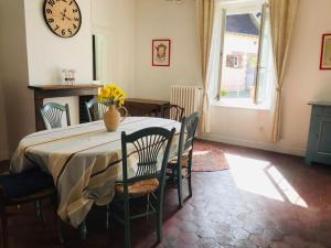 a dining room table with chairs and a clock on the wall at Gîte de la Perdrix 