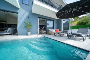 - une piscine avec un parasol à côté d'une maison dans l'établissement Villa Oxy Private Pools & Seaview & Heated Indoor Pool, à Göcek